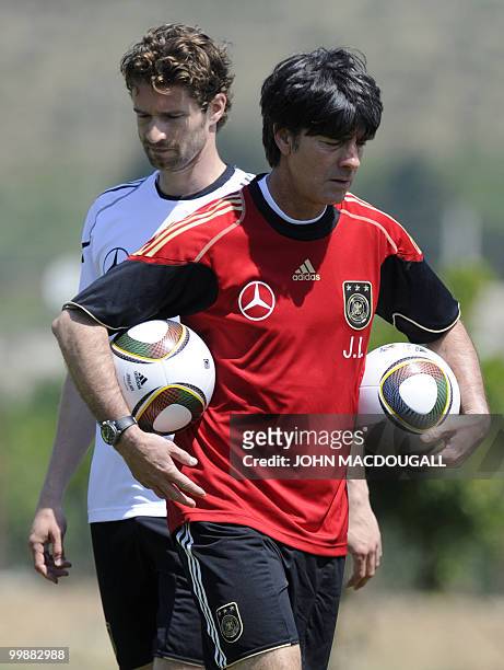 Germany's head coach Joachim Loew walks past Germany's defender Arne Friedrich as he carries ball during a training session at the Verdura Golf and...