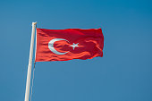 Large flag of Turkey is waving in the wind against the blue sky