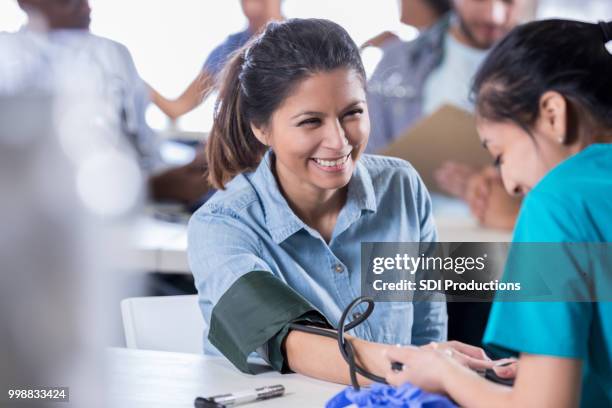 volunteer nurse checks patient's blood pressure - community events stock pictures, royalty-free photos & images