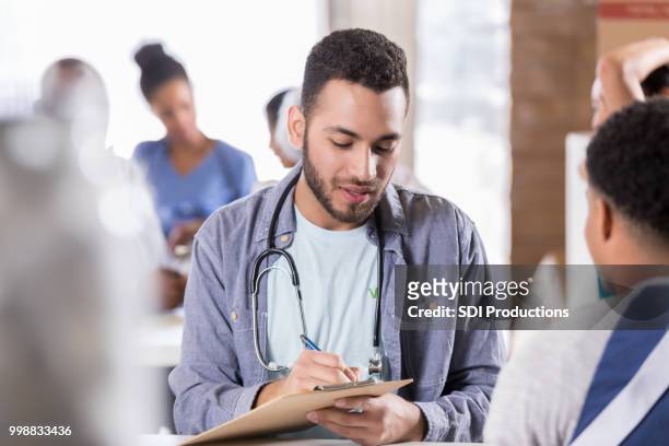 young male doctor volunteers in free clinic - film and television screening stock pictures, royalty-free photos & images