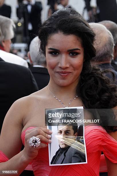French actress Sabrina Ouazani holds a portrait of an actor of the film who recently died as she arrives for the screening of "Des Hommes et des...