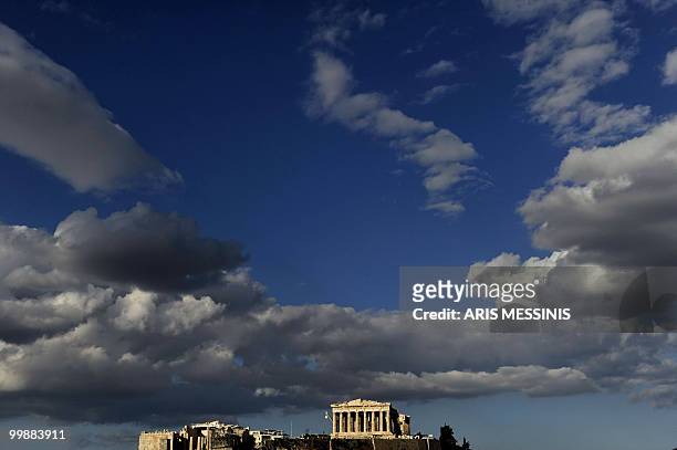 The ancient temple of Parthenon atop the Acropolis hill is illuminated by late evening sunlight in Athens on May 18, 2010. AFP PHOTO / Aris Messinis