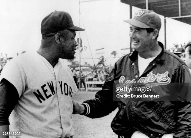 Coach Elston Howard of the New York Yankees and manager Ted Williams of the Washington Senators talk prior to an MLB Spring Training game between the...