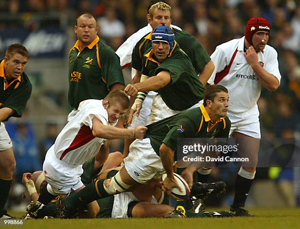 Joost van der Westhuizen of South Africa passes the ball out to his backs as Graham Rowntree of England gets hold of him during the Investec...