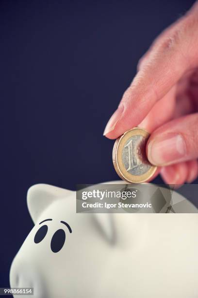 woman putting one euro coin in piggy bank - 庇護者 ストックフォトと画像