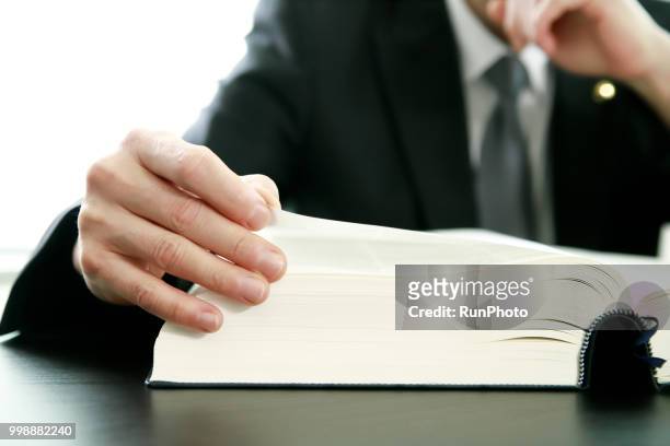 close up of lawyer reading law book at desk - difensore foto e immagini stock