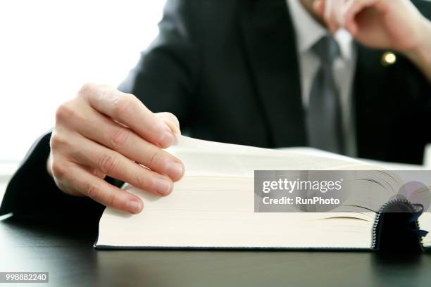 close up of lawyer reading law book at desk - 法律 ストックフォトと画像