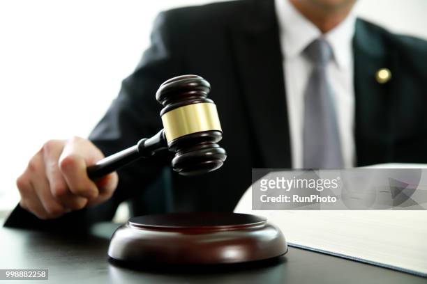 lawyer holding gavel at desk - judgement foto e immagini stock