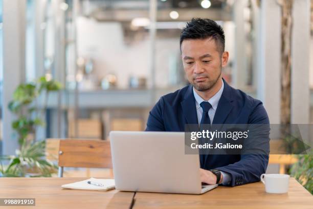 businessman using a laptop in a modern office - jgalione stock pictures, royalty-free photos & images