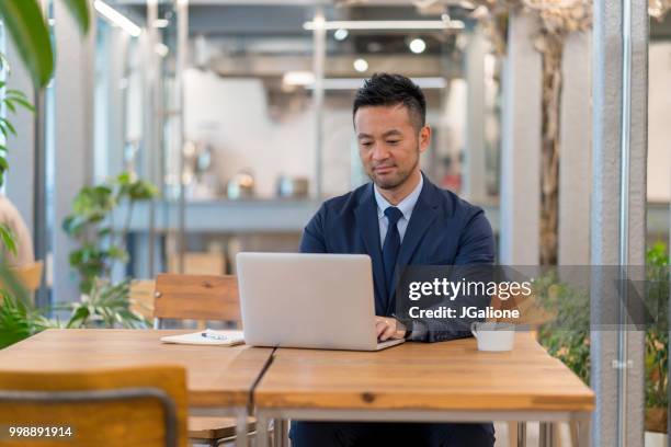 geschäftsmann mit laptop in einem modernen büro - jgalione stock-fotos und bilder