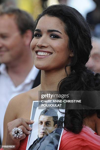 French actress Sabrina Ouazani holds a portrait of an actor of the film who recently died as she arrive for the screening of "Des Hommes et des...