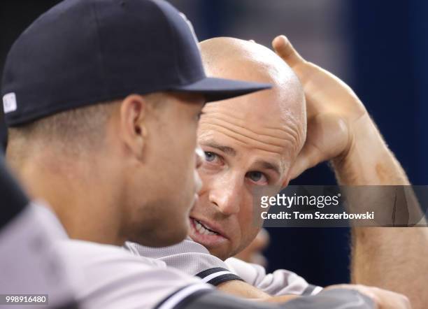 Brett Gardner of the New York Yankees talks to Giancarlo Stanton as they sit on the top step of the dugout during MLB game action against the Toronto...