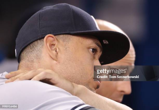 Giancarlo Stanton of the New York Yankees and Brett Gardner look on from the top step of the dugout during MLB game action against the Toronto Blue...