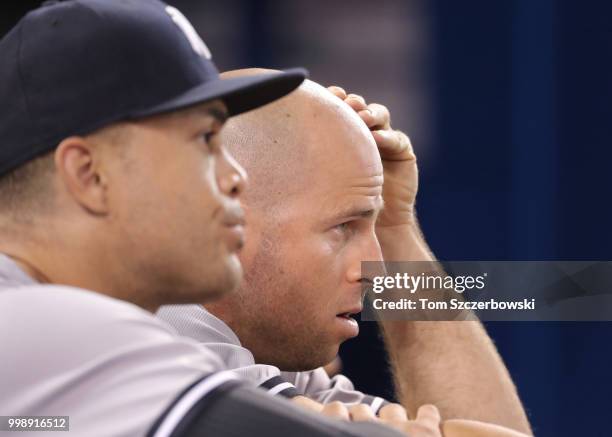 Brett Gardner of the New York Yankees and Giancarlo Stanton look on from the top step of the dugout during MLB game action against the Toronto Blue...