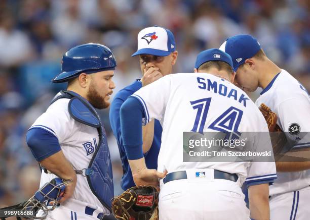 Sam Gaviglio of the Toronto Blue Jays is visited on the mound by pitching coach Pete Walker as Russell Martin listens in the fifth inning during MLB...