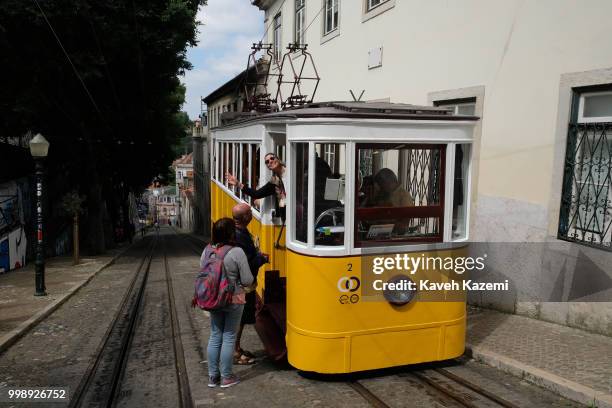 Cable car in a small alley way is used for transporting passengers from elevated Chiado neighborhood to bottom of the hill by Tagus river seen on...