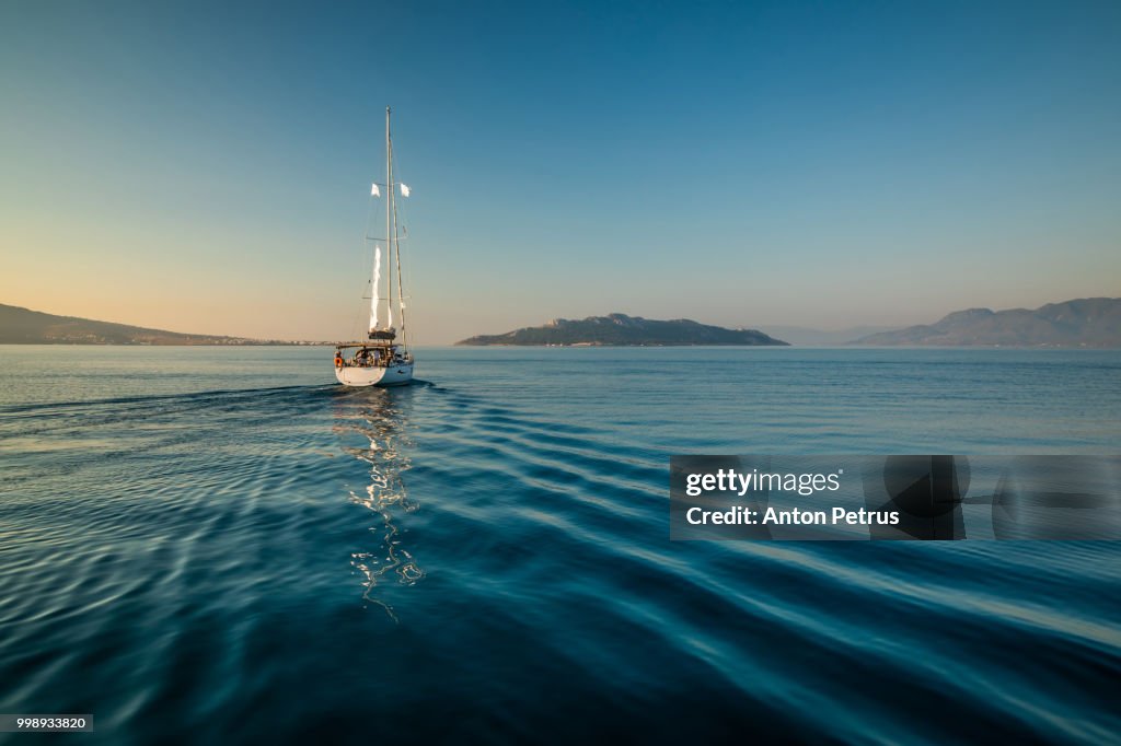 Lonely yacht sailing on silent sea. Aegina Island, Greece