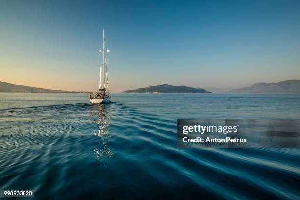 lonely yacht sailing on silent sea. aegina island, greece - yacht de luxe stock-fotos und bilder