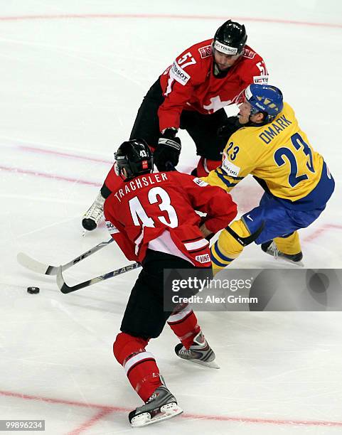 Linus Omark of Sweden is challenged by Goran Bezina and Morris Trachsel of Switzerland during the IIHF World Championship group E qualification round...