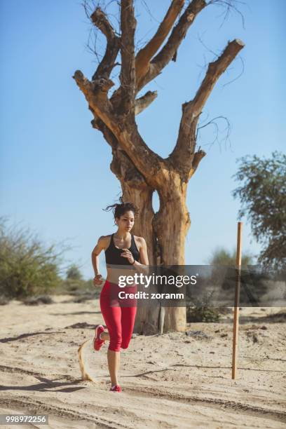 young female runner running past a tree - zoranm imagens e fotografias de stock