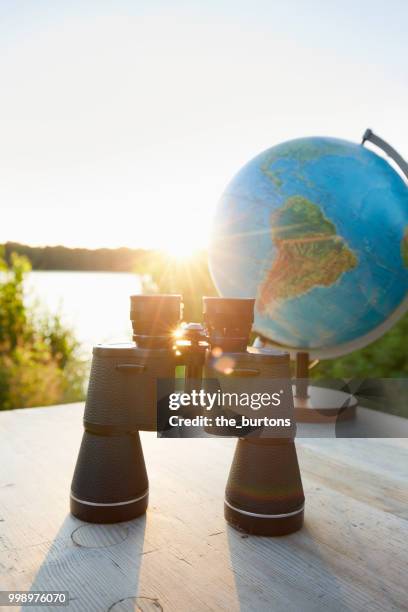 binoculars and globe on a table at lakeside against sky and sunset - worldwide day of play and the carmelo anthony foundation san juan puerto rico stockfoto's en -beelden