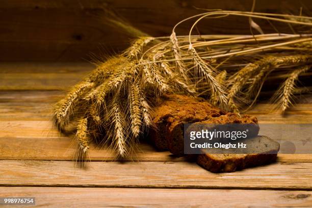 rye bread, a loaf, ears of corn on a background of wooden boards - loaf stock pictures, royalty-free photos & images
