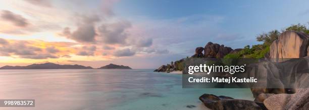 dramatic sunset at anse source d'argent beach, la digue island, seychelles - argent stock-fotos und bilder