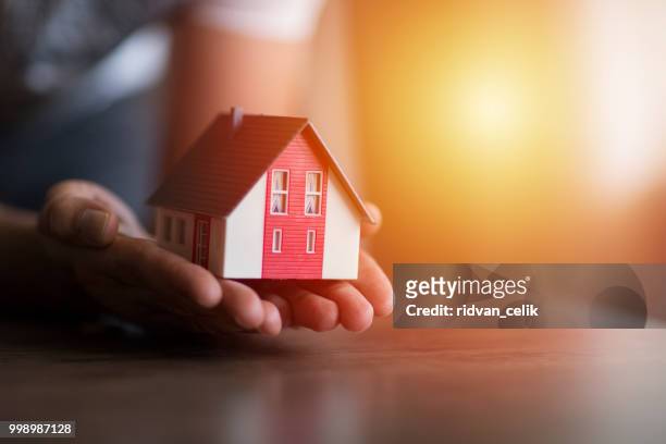 business man hand hold the house model saving small house - at home stock pictures, royalty-free photos & images