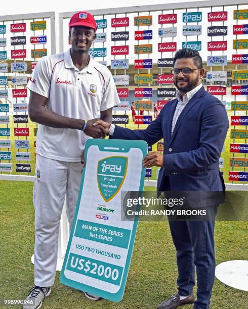 Jason Holder of West Indies receive the man of the series check from Marzanur Rahman at the end of day 3 of the 2nd Test between West Indies and...