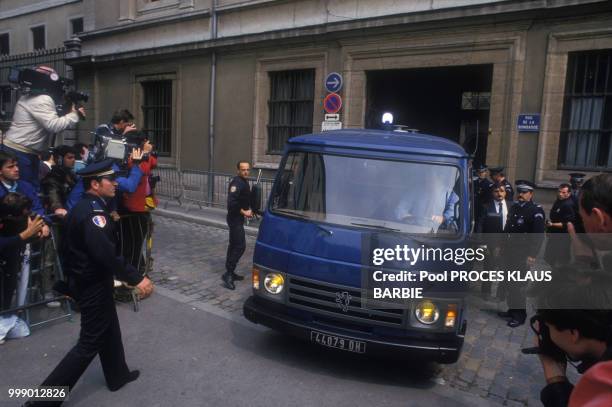 Photographes et caméramen en action devant le vehicule de police transportant Klaus Barbie lors de l'ouverture de son procès le 11 mai 1987 en France.