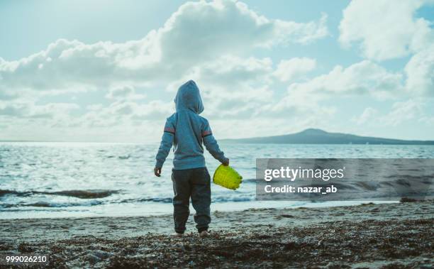 kid with bucket in hand looking towards rangitoto island. - hauraki gulf islands stock pictures, royalty-free photos & images