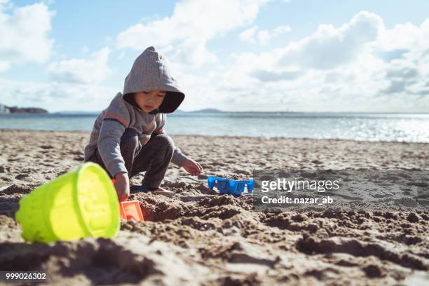 niño jugando en la playa en invierno. - nazar fotografías e imágenes de stock