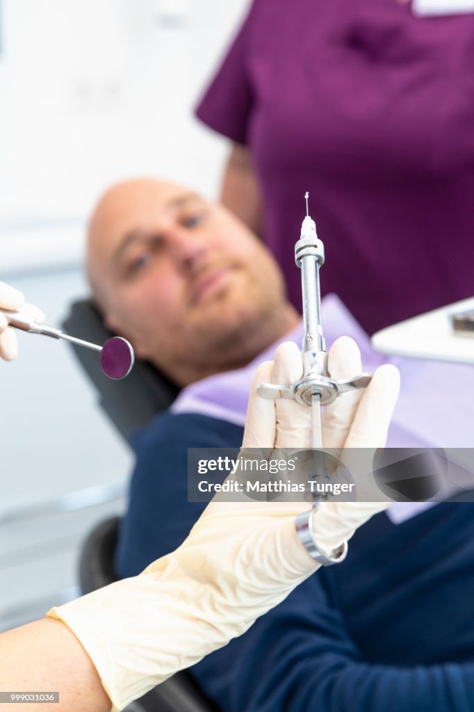 Hand of a dentist holding a loaded injektion