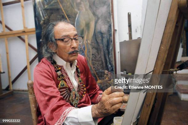 Le peintre Salvador Dali peignant dans son atelier, circa 1970, en Espagne.