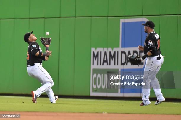 Starlin Castro of the Miami Marlins catches a pop fly while Miguel Rojas looks on during the ninth inning against the Philadelphia Phillies at...