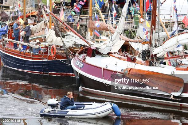 Man in a rubber boat drives past the sailors during the 27th WattenSail and the 30th birthday of the museum harbour in Carolinensiel, Germany, 11...