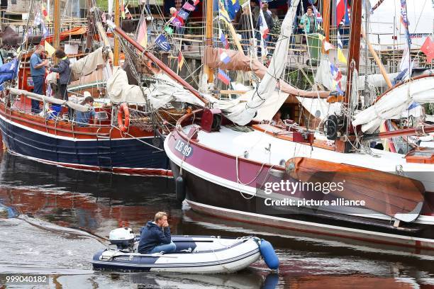 Man in a rubber boat drives past the sailors during the 27th WattenSail and the 30th birthday of the museum harbour in Carolinensiel, Germany, 11...