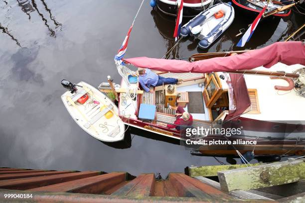 Two sailor sit on a traditional sailing boat during the 27th WattenSail and the 30th birthday of the museum harbour in Carolinensiel, Germany, 11...
