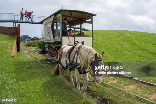 The horse tramway passes by the dyke openings on its scheduled tour in front of the island station on the North Sea island Spiekeroog, Germany, 11...