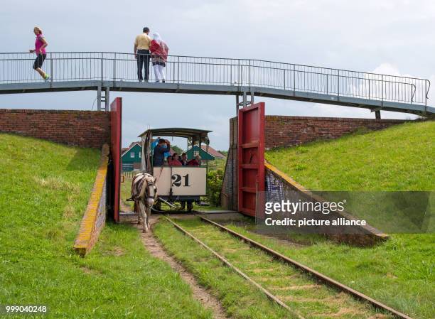 The horse tramway passes by the dyke openings on its scheduled tour in front of the island station on the North Sea island Spiekeroog, Germany, 11...