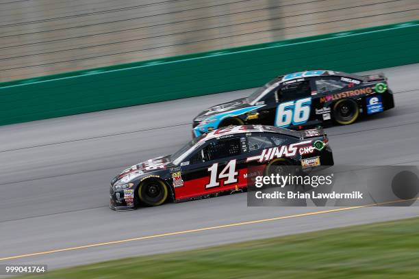 Clint Bowyer, driver of the Haas 30 Years of the VF1 Ford, leads Timmy Hill, driver of the Crypto Crow Toyota, during the Monster Energy NASCAR Cup...
