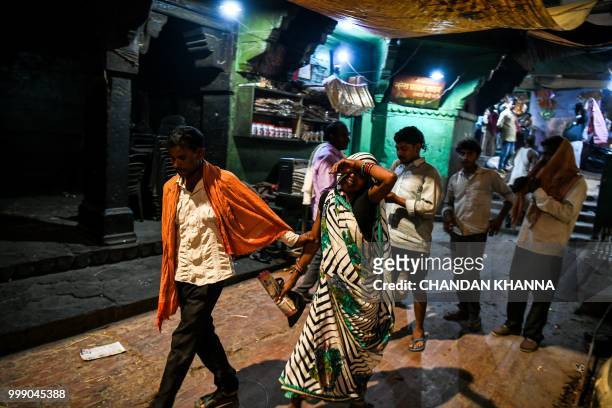 This photo taken on June 2, 2018 shows an Indian man holding his wife as they mourn their son's death, at the Manikarnika ghat in the old quarters of...