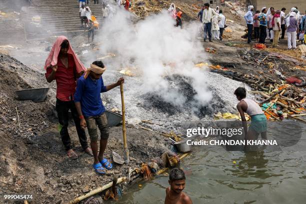 This photo taken on June 2, 2018 shows Indian members of the Dom community extinguishing the ashes of a dead body to search for any valuables like...