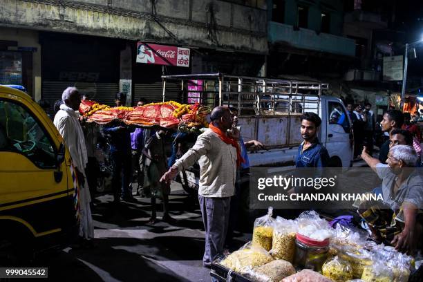 This photo taken on June 2, 2018 shows Indian men unloading a dead body from a van at the Harishchandra ghat in the old quarters of Varanasi. - The...
