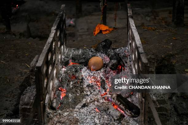 This photo taken on June 2, 2018 shows a dead body burning out at the Manikarnika ghat in the old quarters of Varanasi. - The Doms are a small...