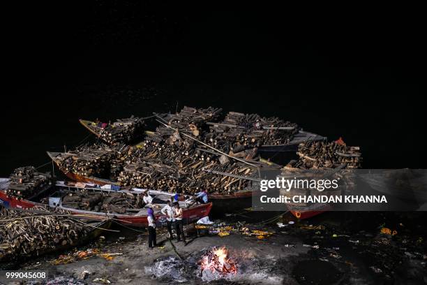 This photo taken on June 2, 2018 shows Indian men waiting for a dead body to finish being cremated at the Manikarnika ghat in the old quarters of...