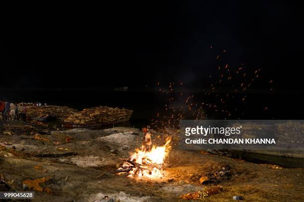 This photo taken on June 1, 2018 shows an Indian member of the Dom community tending to a funeral pyre at the Manikarnika ghat in the old quarters of...