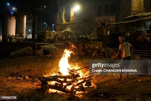 This photo taken on June 1, 2018 shows an Indian member of the Dom community tending to a funeral pyre at the Manikarnika ghat in the old quarters of...