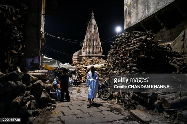 This photo taken on June 2, 2018 shows an Indian man walking through the Manikarnika ghat in the old quarters of Varanasi. - The Doms are a small...