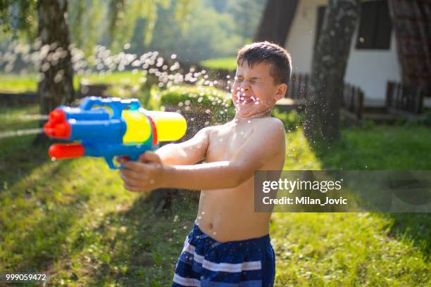 little boy splashing with water gun - jovic stock pictures, royalty-free photos & images